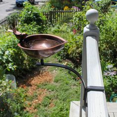 a metal bowl sitting on top of a wooden rail