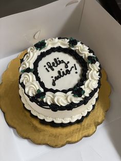 a white and black cake sitting on top of a gold plate in a cardboard box