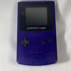 a game boy color sitting on top of a white sheet with the screen turned off