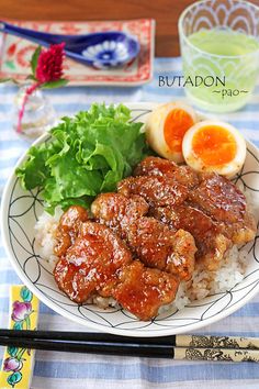 a plate with rice, meat and vegetables on it next to chopsticks and orange slices