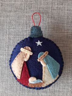 a christmas ornament with two small ornaments hanging from it's side on a gray surface