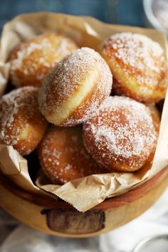 powdered sugar covered donuts in a wooden bowl