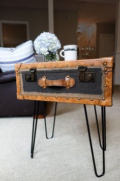 an old suitcase is sitting on some hairpin legs in front of a coffee table