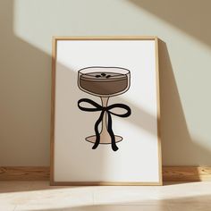 an art print with a wine glass and bow on the bottom, in front of a wall