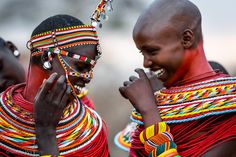 two women in colorful headdresses and necklaces are standing next to each other