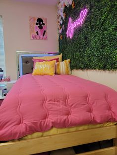 a bed with pink sheets and pillows in front of a green wall that says happy new year