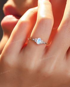 a woman's hand with a ring on her finger and an opal stone in the middle