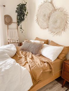 a bed with pillows and blankets on top of it next to a potted plant