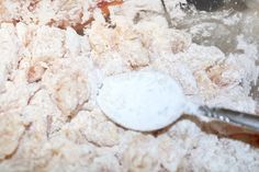 powdered sugar is being mixed together in a mixing bowl with a spoon on the side