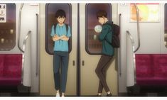 two people standing in front of the doors of a subway car with their arms crossed