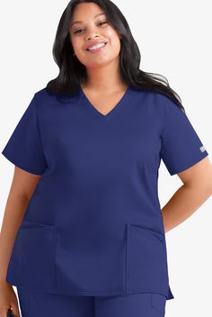 Fit for plus-size women, our short-sleeve style has strategically placed front and back darts for an incredibly flattering, streamlined look. Each piece in our Butter-soft Stretch scrub collection was designed for 12+ hour shifts, and made from easy-care, 2-way stretch comfort fabric. • Relaxed fit • V-neck • Total of 4 pockets • 2 front double pockets • Front and back darts • Short sleeve • Side slits • Approximate length for size 1x is 29 The key to comfort? Cotton and 2-way stretch. They’ve m Stylish Scrubs For Women Plus Size, Plus Size Nurse Scrubs, Plus Size Scrubs Woman Medical, Target Scrub Top, Maternity Scrub Top, Uniform Advantage, Medical Uniforms, Scrubs Nursing, Scrub Tops