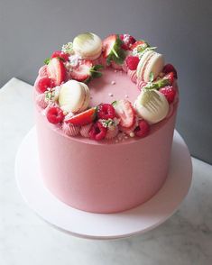 a pink cake with strawberries, bananas and other fruit toppings on the top