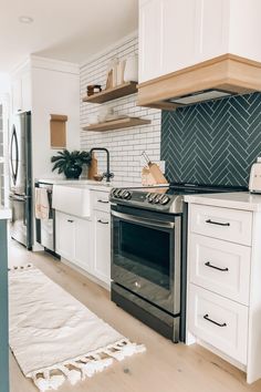 a kitchen with white cabinets, black and silver stove top oven and wood flooring