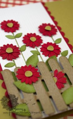 a card with red flowers on it and a fence made out of wood planks