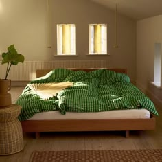 a bed with green and white checkered sheets in a room next to two windows