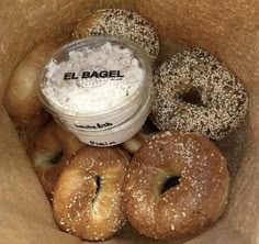 bagels and cream in a paper bag with a container on the side, sitting next to each other