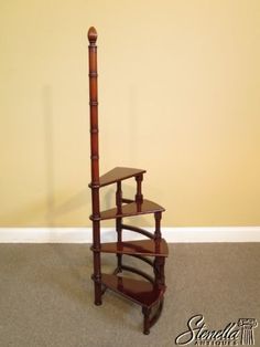 a wooden shelf with three tiers on top of it in front of a yellow wall