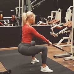 a woman is doing squats in the gym