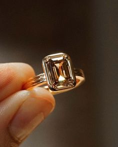 a person is holding an engagement ring with a large green diamond in it's center