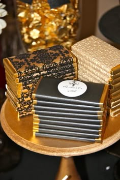 several stacks of cake sitting on top of a wooden table next to gold and black decorations