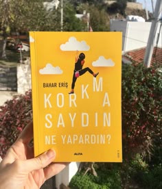 a person holding up a yellow book in front of some bushes and trees, with the title korna saydin ne yapadrdin?