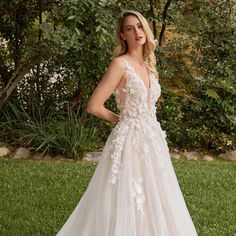 a woman in a wedding dress standing on the grass