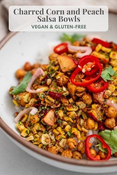 a white bowl filled with chopped corn and peach salsa bowls topped with red bell peppers