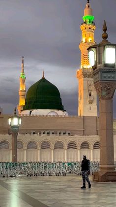 a person standing in front of a large building with two green and white domes at night