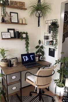 a laptop computer sitting on top of a wooden desk next to a potted plant