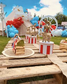 a wooden table topped with boxes filled with cake next to balloons and other decorations on top of it