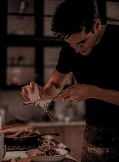 a man in black shirt preparing food on top of a white plate with graters