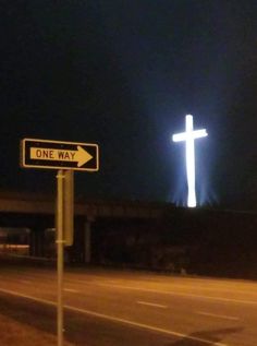 a street sign with a cross in the background