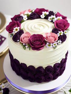 there is a white and purple cake with flowers on the top, sitting on a table