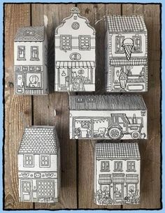 four paper houses are sitting on a wooden table