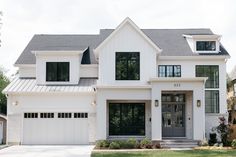 a white two story house with black windows