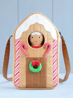 a gingerbread house shaped purse with candy canes on the front and an elf in the back