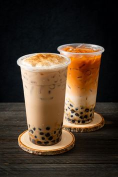 two iced drinks sitting on top of wooden coasters