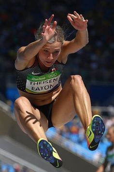 a woman jumping in the air on top of a track