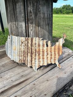 an old rusted metal usa map sitting on top of a wooden table in front of a barn