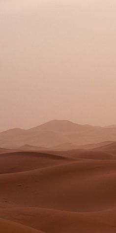 two people riding horses in the desert with sand dunes behind them and mountains in the distance