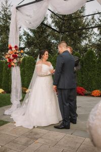 a bride and groom standing under an outdoor gazebo at their wedding ceremony in the fall