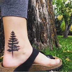 a woman's foot with a tree tattoo on it