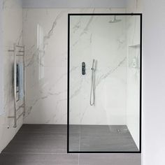 a bathroom with marbled walls and flooring is pictured in this image, it has a glass shower door