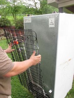 a man is pointing at the side of a refrigerator that's attached to a fence