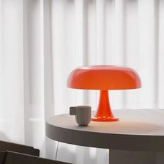 an orange lamp sitting on top of a table next to a cup and saucer