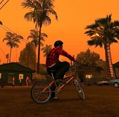 a man riding a bike down a street next to palm trees