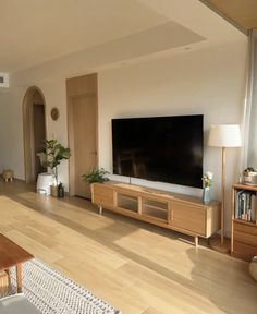 a large flat screen tv sitting on top of a wooden shelf in a living room