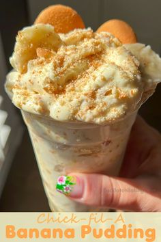 a hand holding an ice cream sundae with oranges in the background and text that reads, chick - fil's banana pudding