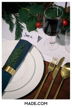 the place setting is set with silverware, napkins and gold utensils