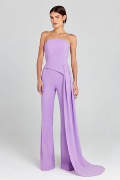 a woman in a strapless purple jumpsuit is standing with her hands on her hips